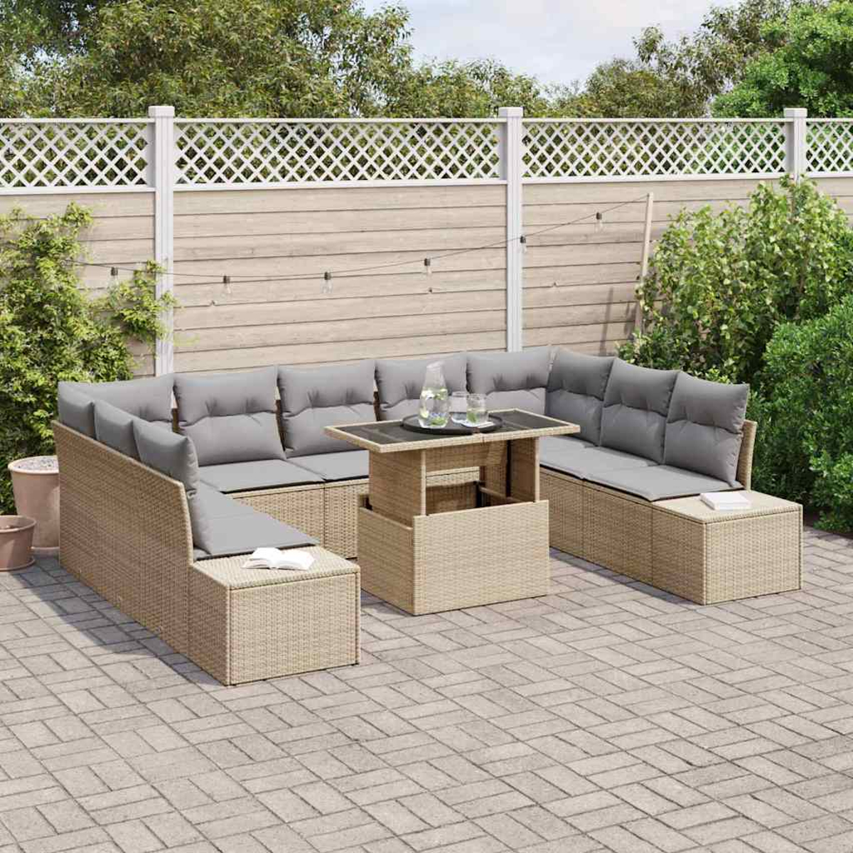 Garten-Terrassenset mit beigen Korbmöbeln, grauen Kissen, einem Tisch und einem weißen Zaun im Hintergrund.