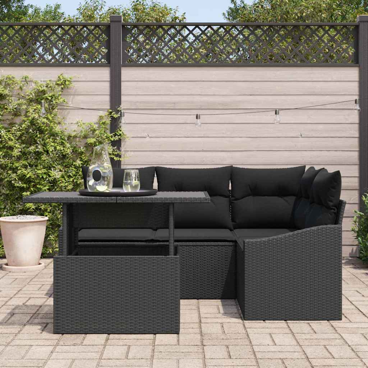 Eine Outdoor-Umgebung mit einem schwarzen Korbsessel, Tisch und Kissen. Ein Glas Wasser, eine Wasserkaraffe und ein Zaun sind ebenfalls sichtbar.