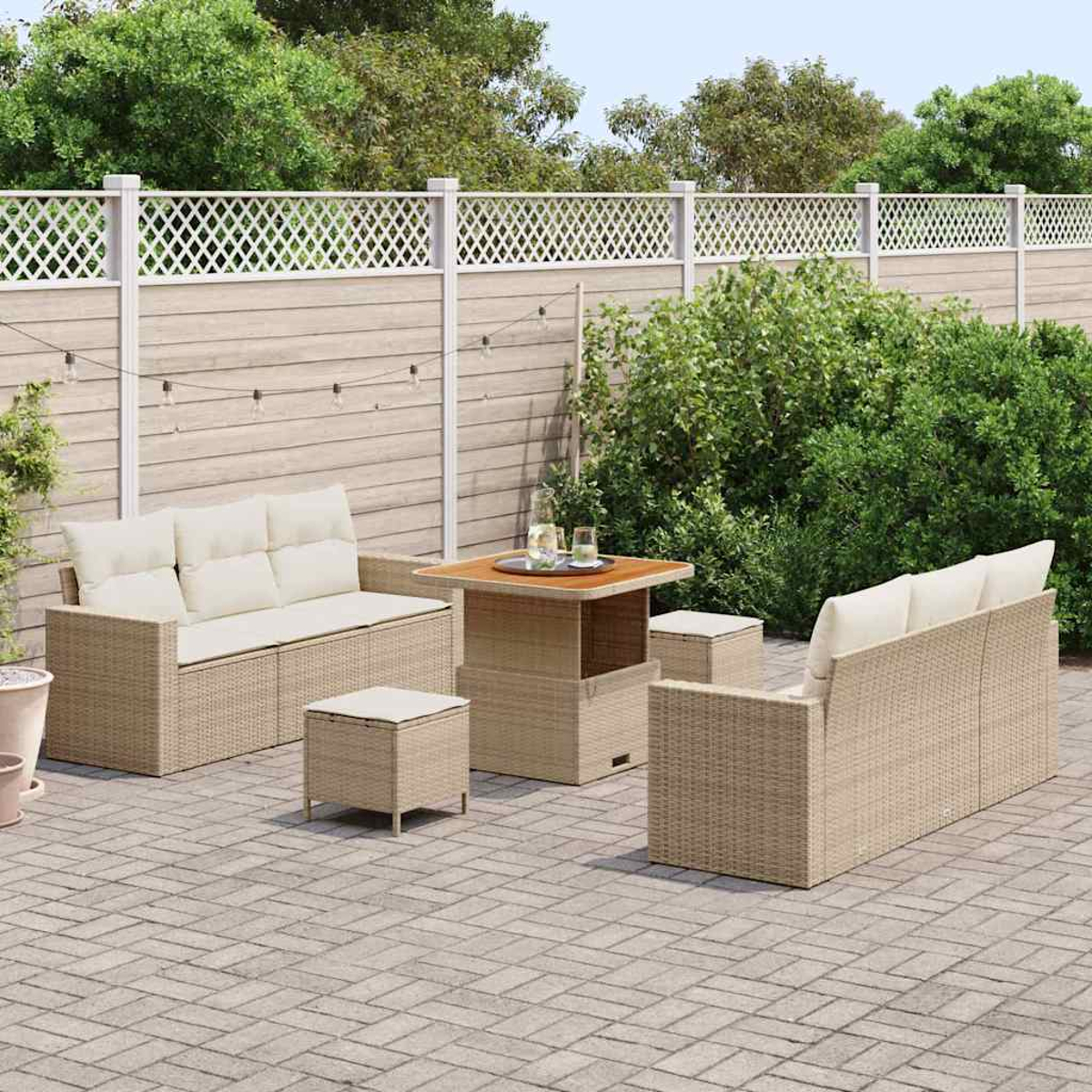 Garten-Terrassenset: Korbsessel und -hocker um einen Tisch auf einer Ziegelsteinterrasse, mit einem Gitterzaun und Grün im Hintergrund.