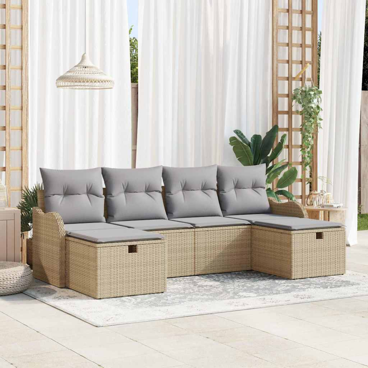 Ein beiges Outdoor-Ecksofa aus Korbgeflecht mit grauen Kissen steht auf einem Teppich. Weiße Vorhänge und eine Hängeleuchte sind im Hintergrund.