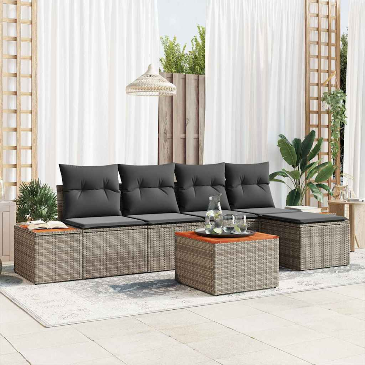 Rattan-Sofa im Freien mit grauen Kissen und einem Tisch mit Gläsern. Weiße Vorhänge und Pflanzen im Hintergrund schaffen eine entspannte Szene.