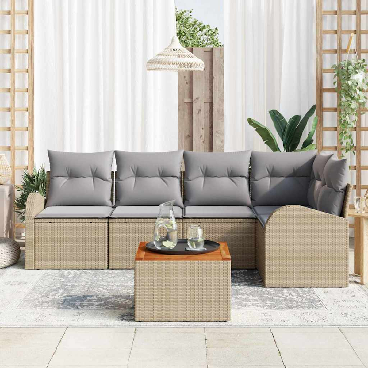 Garten-Sitzgruppe mit grauen Kissen, Couchtisch mit Wasser und Hängelampe. Weiße Vorhänge und Holzgitter im Hintergrund.