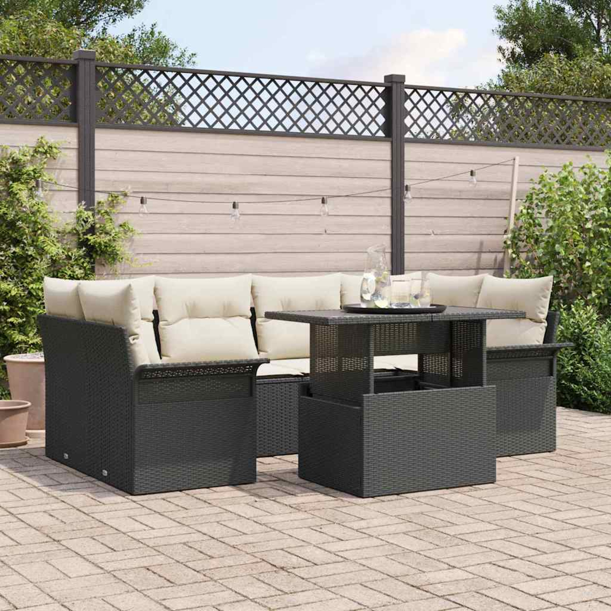 Garten-Sitzgruppe mit grauen Möbeln, cremefarbenen Kissen und einem Tisch mit Hubfunktion auf einer Ziegelterrasse. Holzzaun im Hintergrund.