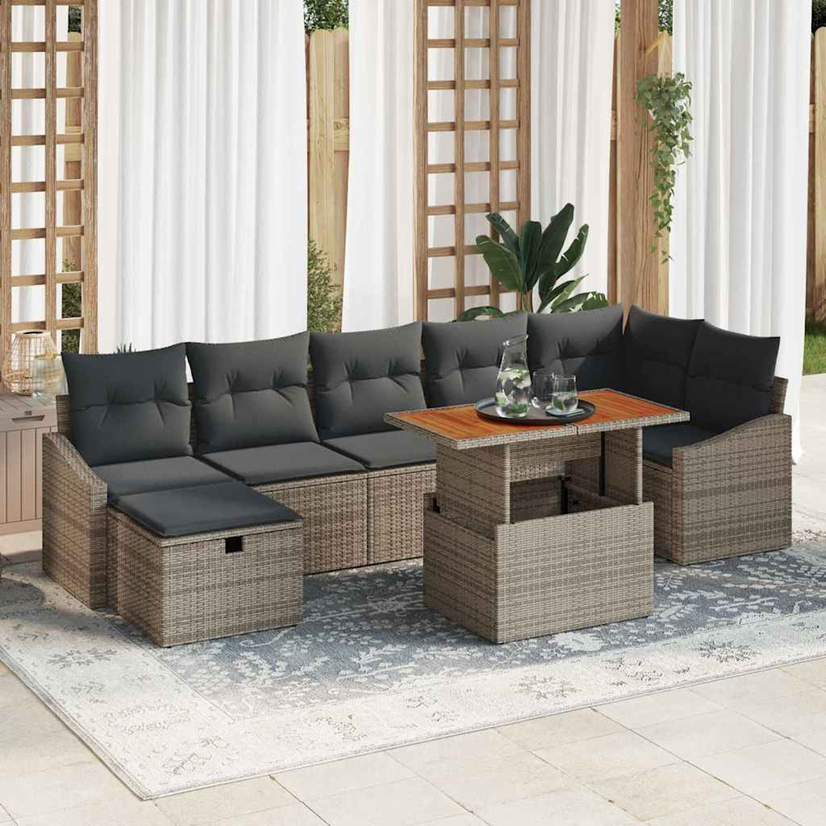 Outdoor-Ecksofa aus Korbgeflecht mit grauen Kissen, einem Holztisch und einem Teppich. Im Hintergrund weiße Vorhänge und ein Holzgitter.