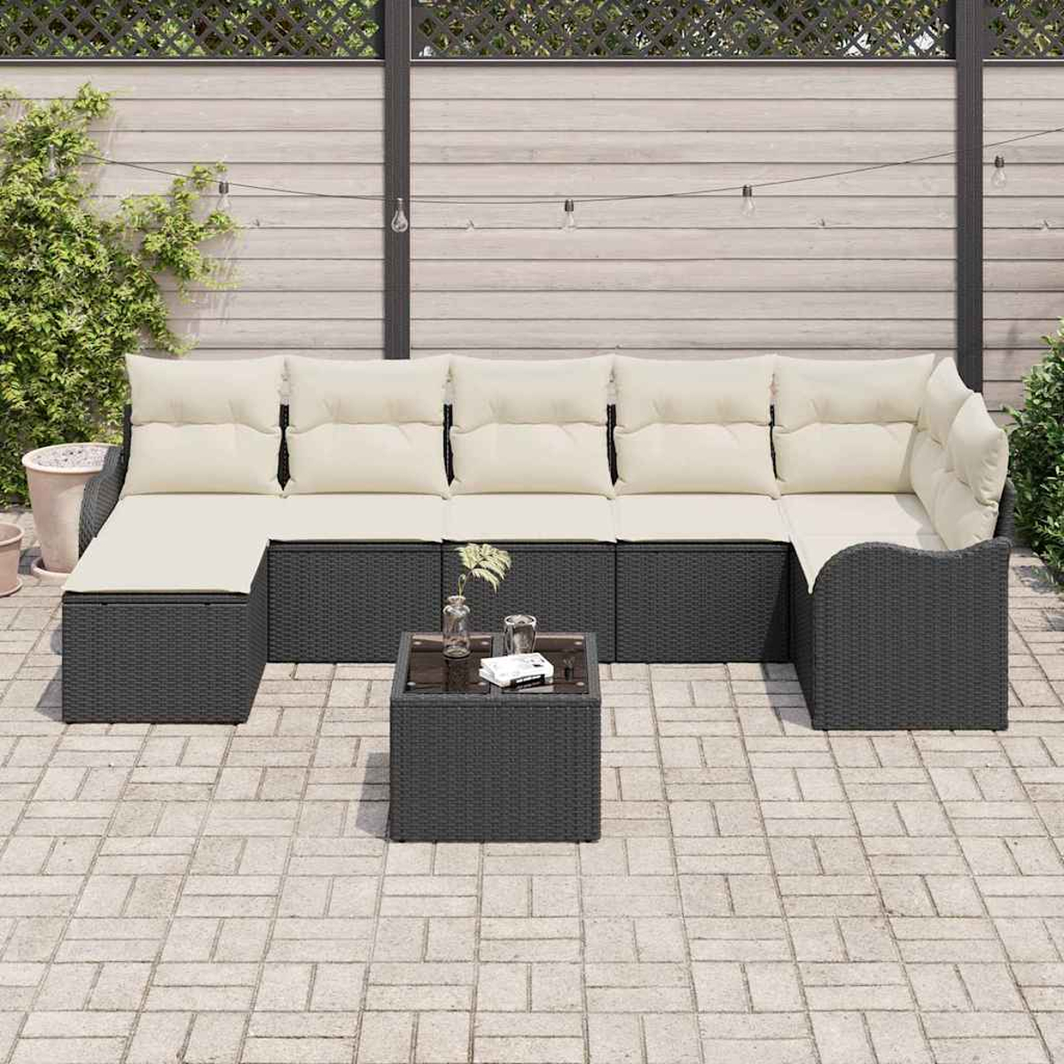 Outdoor-Ecksofa mit cremefarbenen Kissen und einem kleinen quadratischen Tisch auf einer Ziegelterrasse. Im Hintergrund ein Holzzaun.