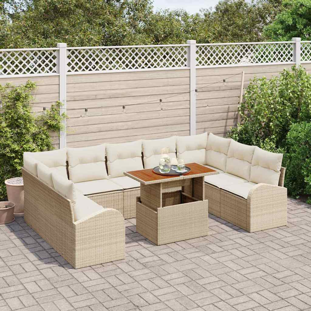 Outdoor-Sitzbereich mit beigen Korbmöbeln, cremefarbenen Kissen und einem Holztisch. Im Hintergrund sind ein Zaun und Grün zu sehen.
