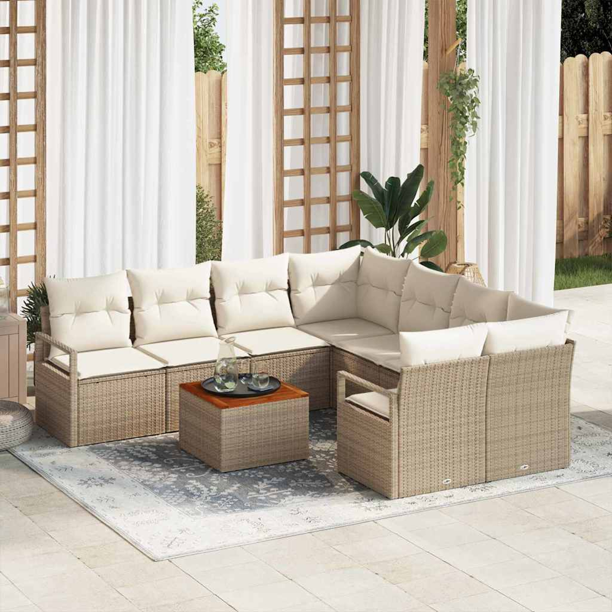 Outdoor-Ecksofa mit cremefarbenen Kissen, Couchtisch, Teppich und weißen Vorhängen. Hintergrund mit Holzzaun und Grün.