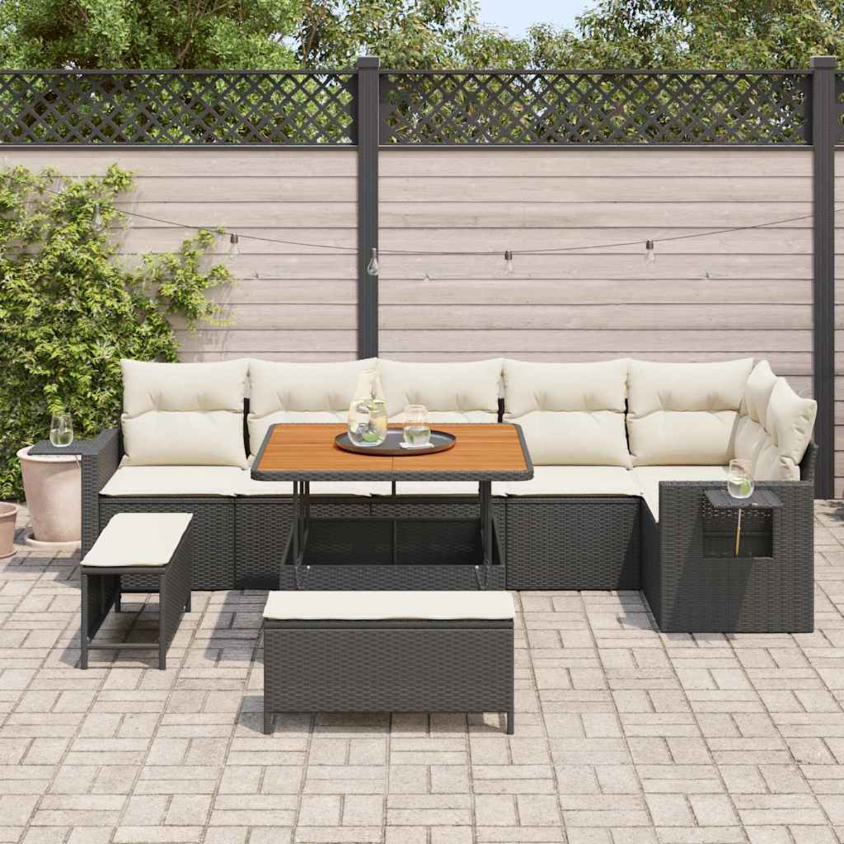 Terrassenmöbel-Set mit Ecksofa, Tisch mit Tablett, zwei Ottomanen und einem Hintergrund aus Zaun und Grün.