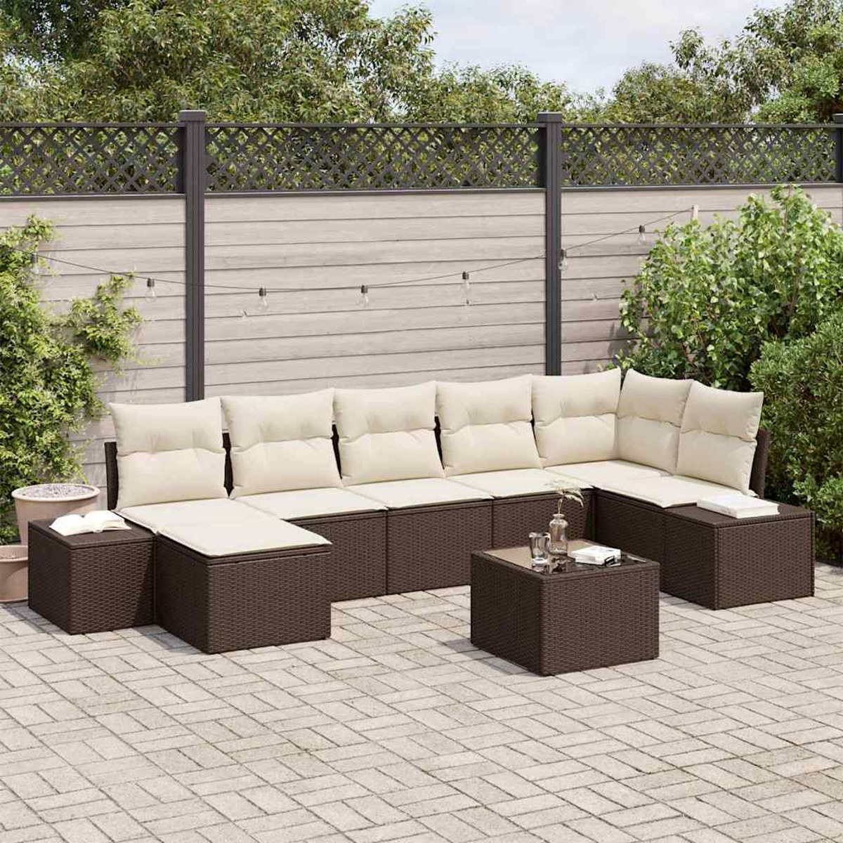 Outdoor-Ecksofa mit cremefarbenen Kissen und braunem Korbgewebe, ein kleiner Tisch auf einer gepflasterten Terrasse mit Zaun und Laub im Hintergrund.