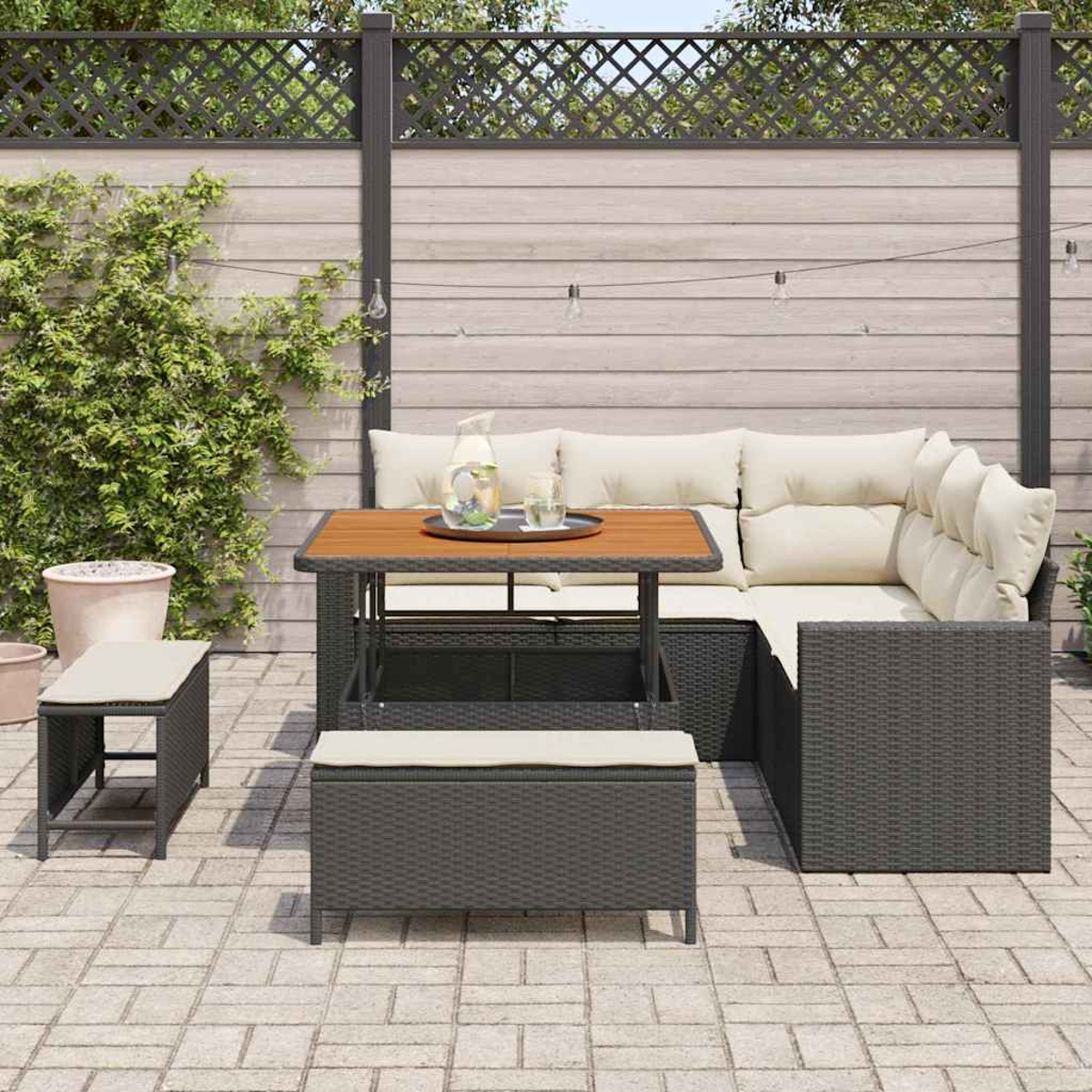 Terrassenmöbel mit Tisch, Ecksofa und zwei Bänken. Kanne und Gläser stehen auf dem Tisch. Der Hintergrund ist ein Holzzaun.