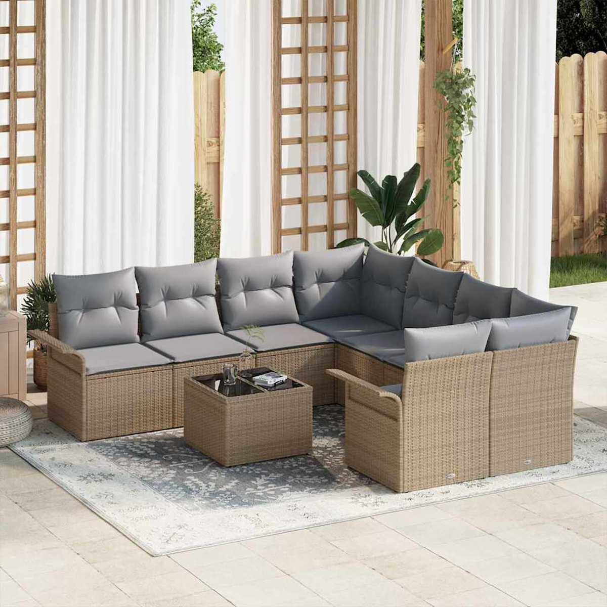 Outdoor-Ecksofa mit grauen Kissen, Couchtisch und Teppich auf einer Terrasse. Hintergrund sind weiße Vorhänge und Holzzaun.