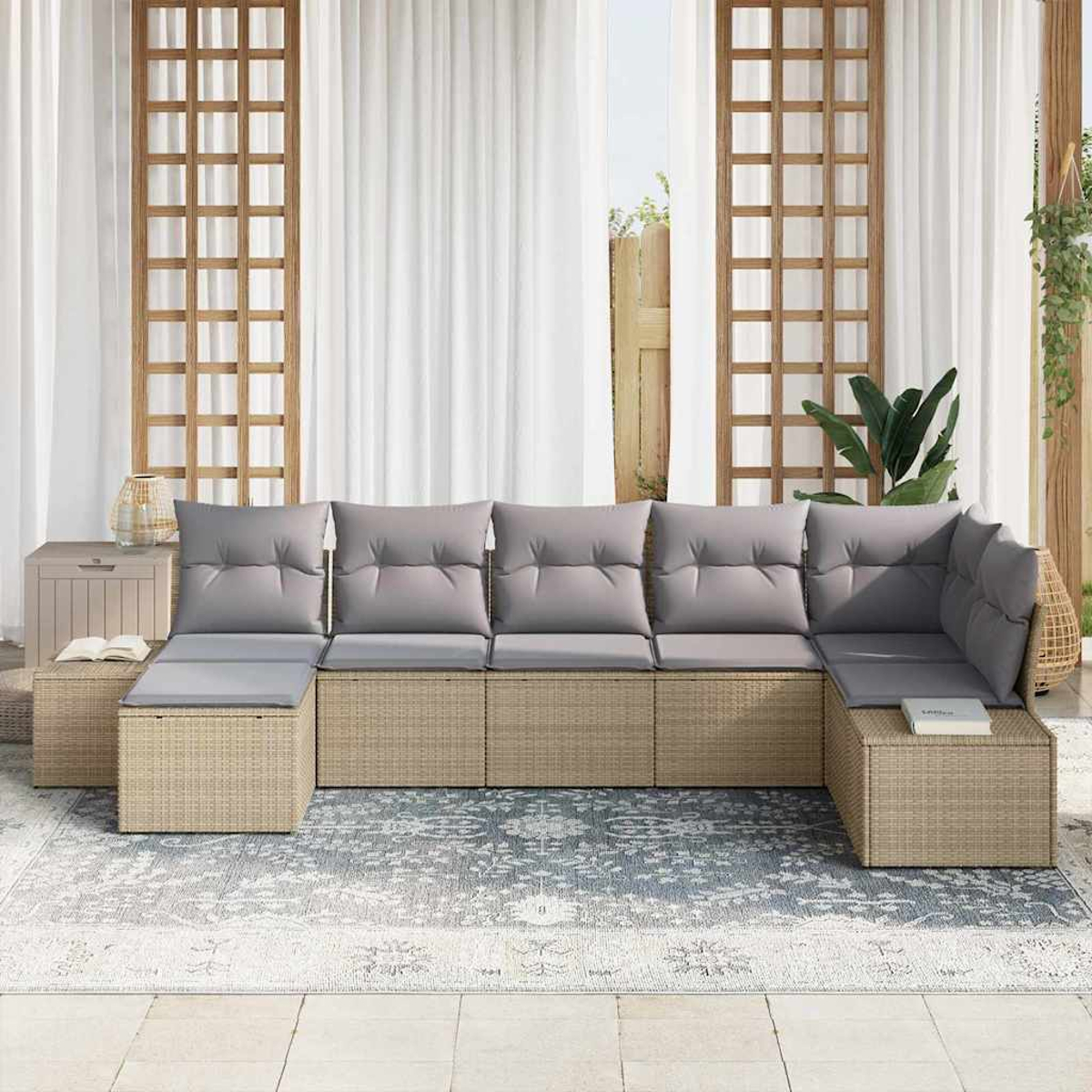 Ein beigefarbenes Ecksofa mit grauen Kissen steht auf einem gemusterten Teppich. Der Hintergrund umfasst weiße Vorhänge und Holzgitter.