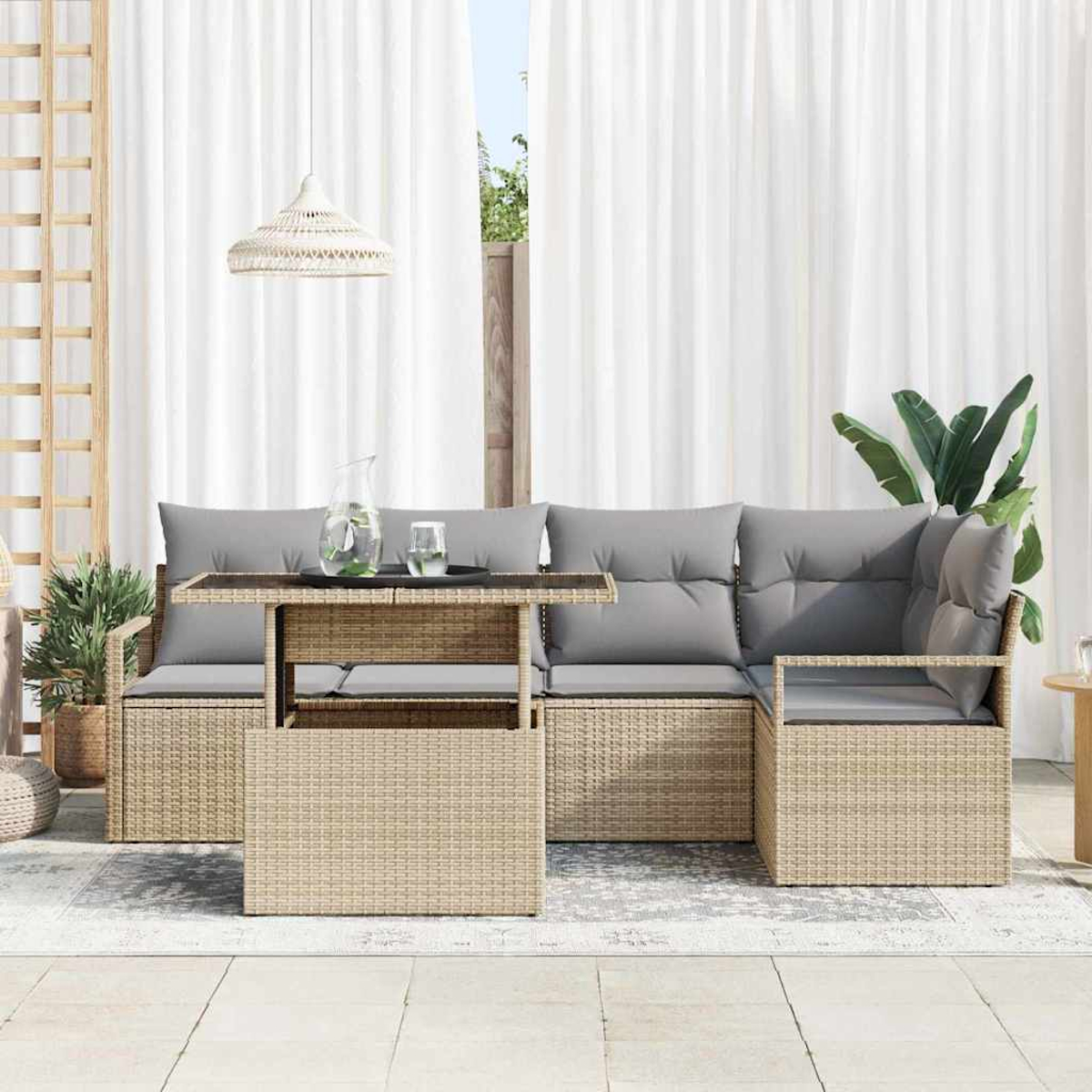 Outdoor-Rattan-Sofagarnitur mit grauen Kissen und einem Tisch. Weiße Vorhänge und Pflanzen sind im Hintergrund. Eine Pendelleuchte hängt darüber.