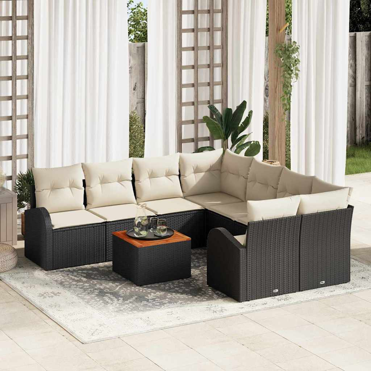 Outdoor-Ecksofa mit beigefarbenen Kissen, schwarzem Korbgewebe und einem kleinen Holztisch auf einem Teppich. Weiße Vorhänge im Hintergrund.