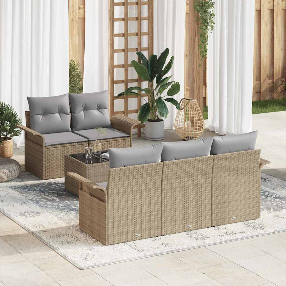 Gartenmöbel-Set mit grauen Kissen. Enthält ein Sofa, ein Sofa und einen Couchtisch auf einem gemusterten Teppich. Pflanzen und Vorhänge im Hintergrund.