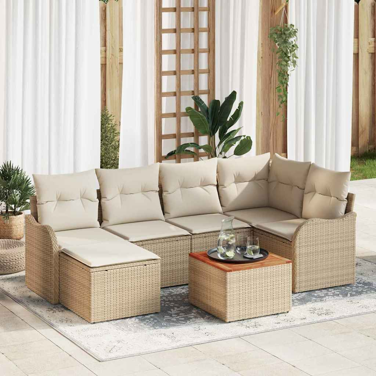 Outdoor-Ecksofa mit beigen Kissen und gewebter Basis. Ein Tisch mit Getränken steht auf einem Teppich. Weiße Vorhänge und Pflanzen im Hintergrund.