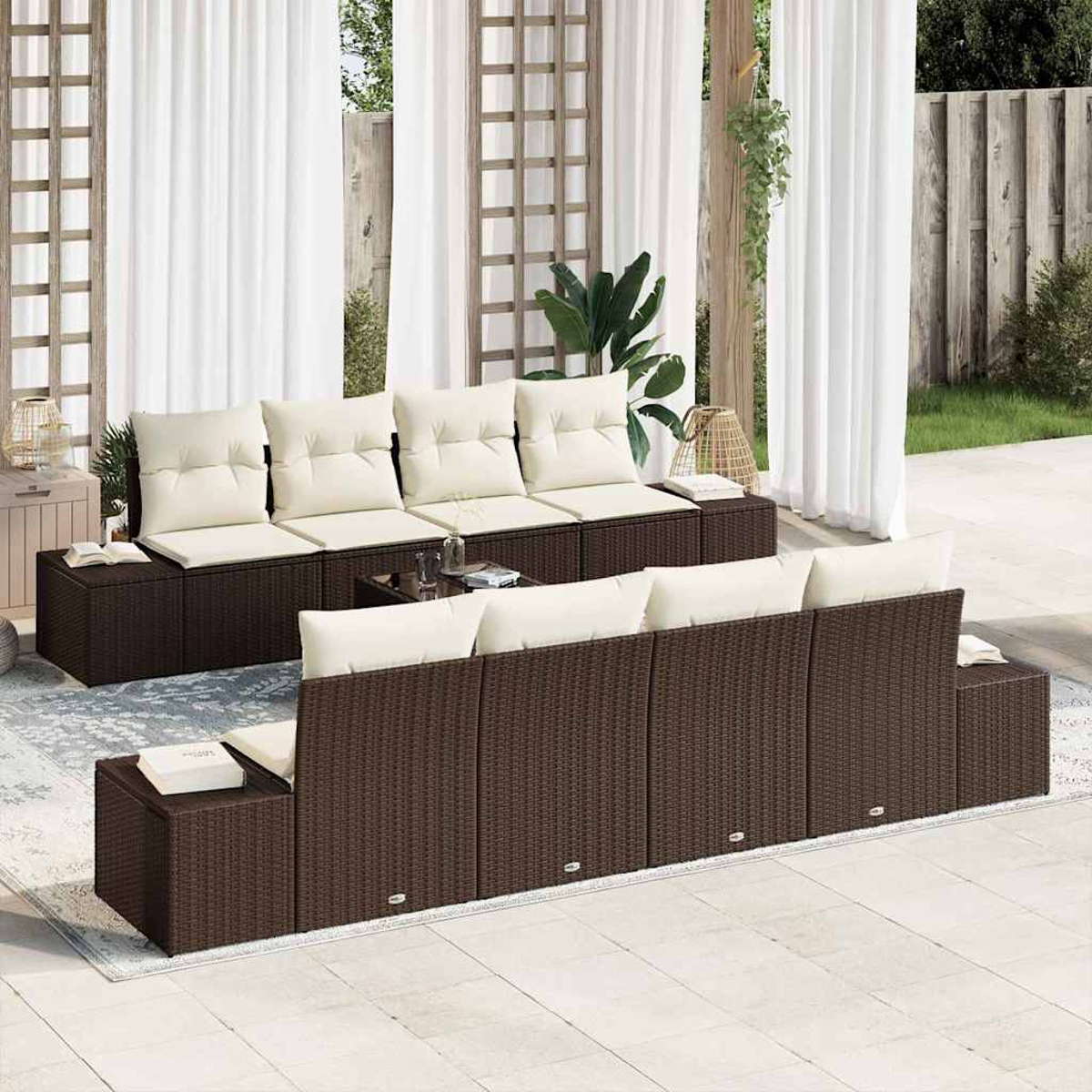 Outdoor-Rattan-Sofa mit cremefarbenen Kissen. Weiße Vorhänge und ein kleiner Tisch mit Gläsern. Hintergrund: Pflanzen und Holzstruktur.