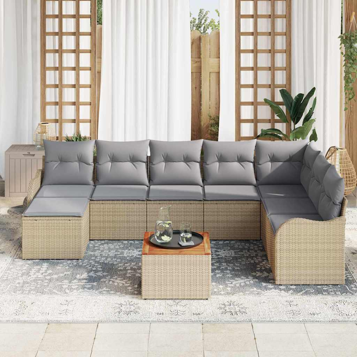 Outdoor-Ecksofa mit grauen Kissen, einem kleinen Tisch mit Getränken und einem gemusterten Teppich. Hintergrund sind Vorhänge und Pflanzen.