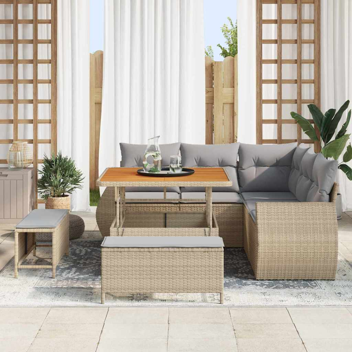 Garten-Terrassenset mit Sofa, Tisch und Bänken. Hellbraune Korbmöbel mit grauen Kissen. Weiße Vorhänge und Pflanzen.