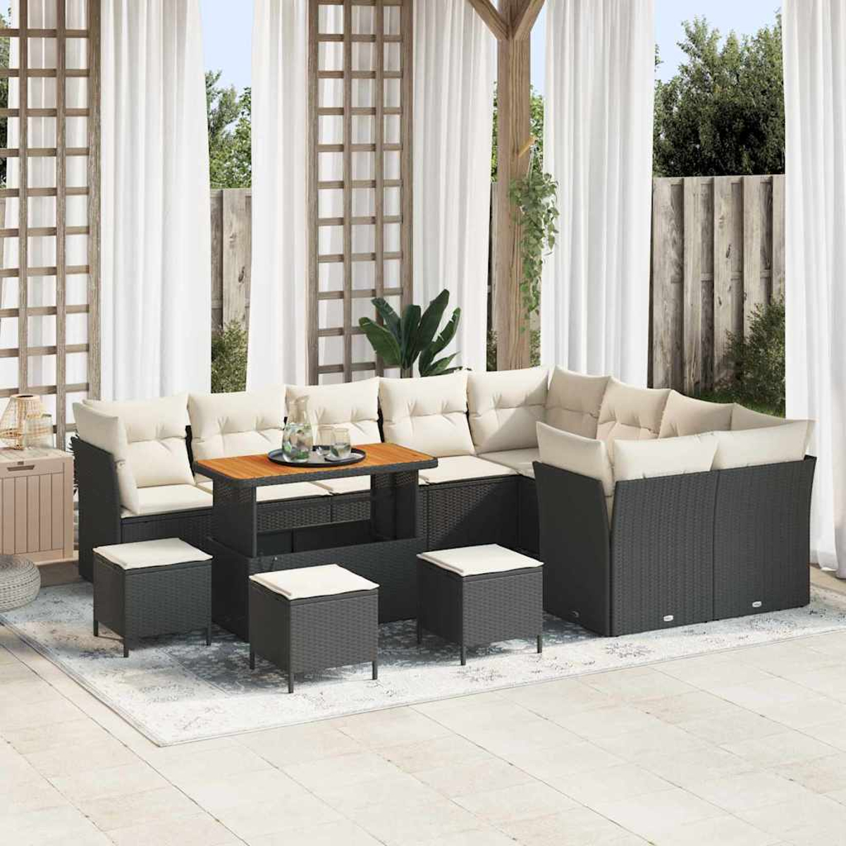 Outdoor-Ecksofa mit cremefarbenen Kissen, einem Holztisch und vier schwarzen quadratischen Hockern auf einem gemusterten Teppich, in der Nähe weißer Vorhänge.
