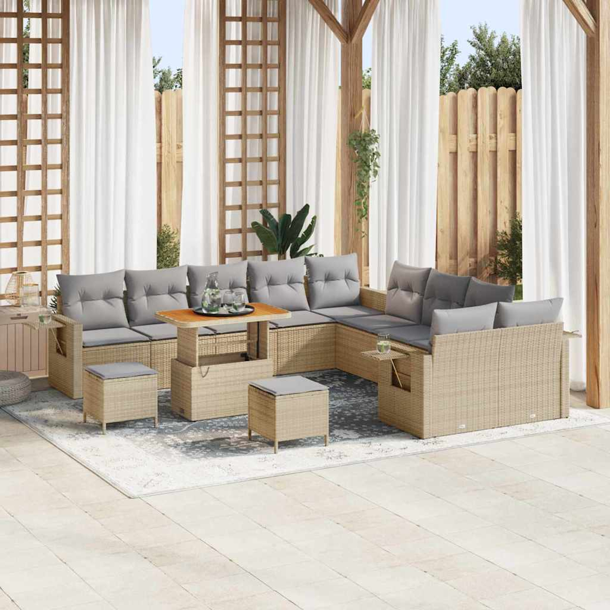 Outdoor-Sitzbereich mit gewebten Möbeln, grauen Kissen, einem Holztisch und weißen Vorhängen. Ein Teppich liegt auf der Terrasse.