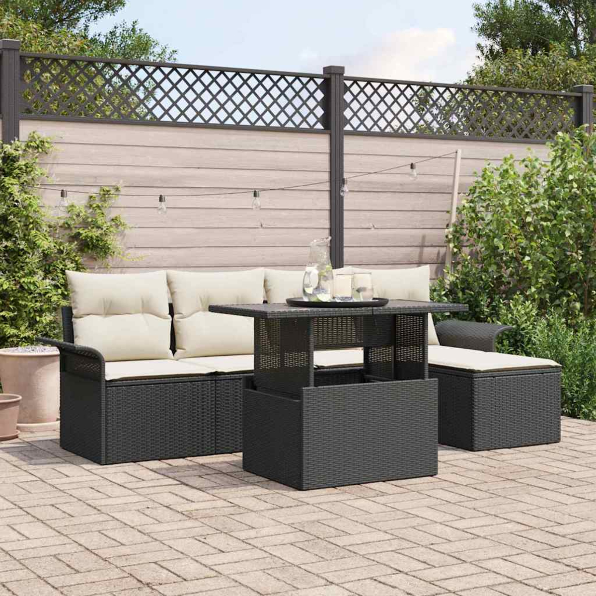 Garten-Terrassenset mit schwarzen Korbmöbeln und beigen Kissen, einem Tisch mit Hebefunktion und einem Zierzaun.