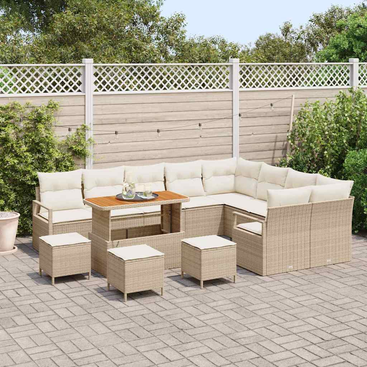Garten-Sitzgruppe auf einer Terrasse. Beige Korbmöbel umfassen ein Ecksofa, Stühle, Hocker und einen Tisch mit cremefarbenen Kissen.