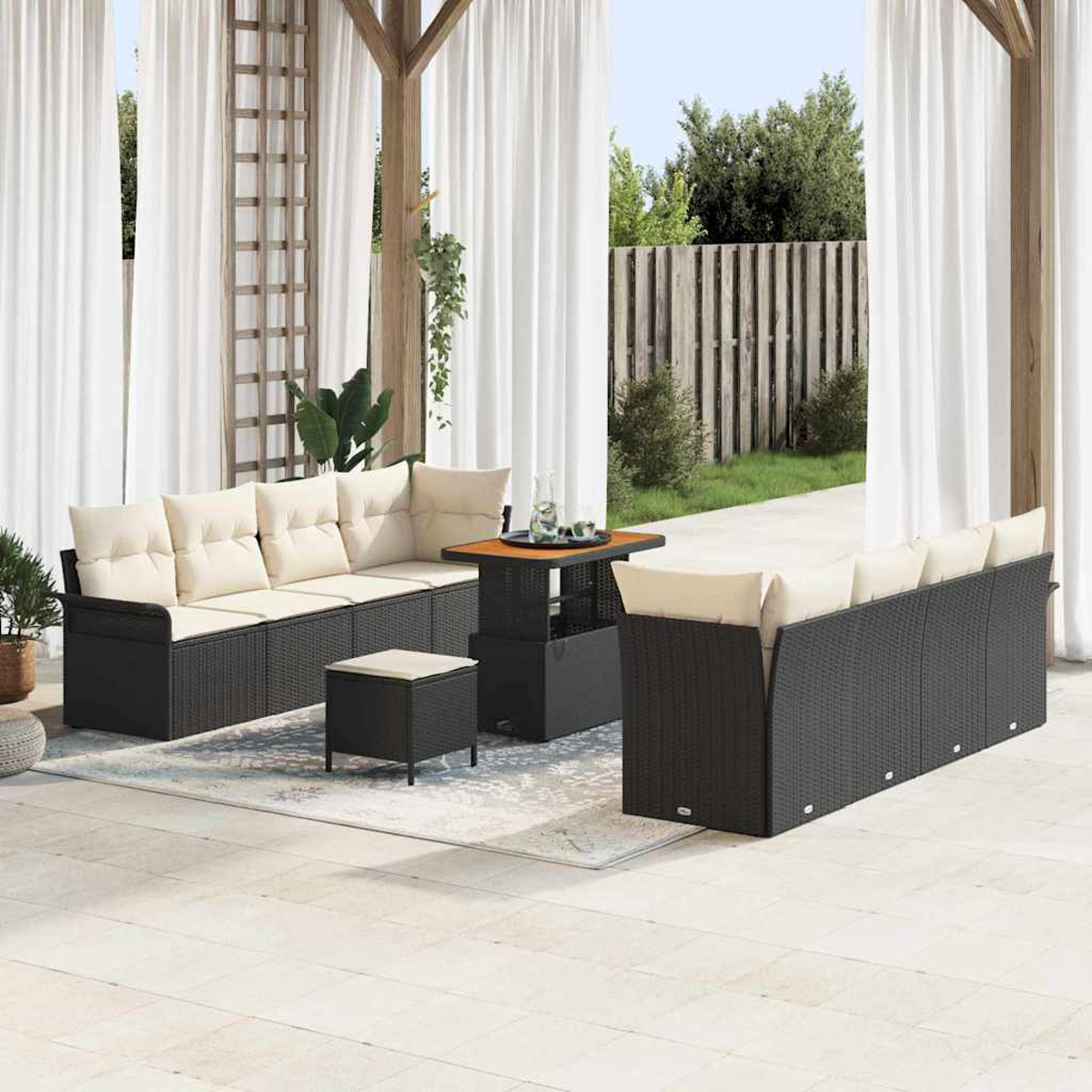 Terrassenset im Freien mit schwarzen Korbmöbeln und cremefarbenen Kissen. Enthält einen Tisch und Vorhänge im Hintergrund.