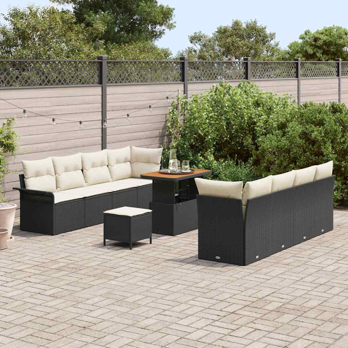 Gartenmöbel-Set. Schwarze Korbsessel mit cremefarbenen Kissen, einem kleinen Tisch und einem Hocker auf einer Ziegelterrasse.