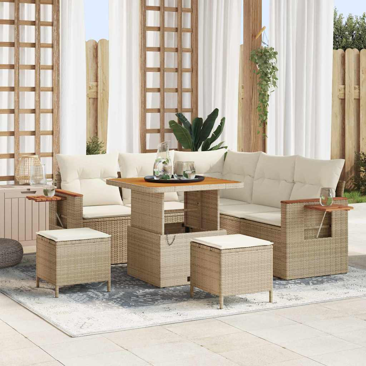 Terrassenset im Freien mit gewebten beigen Möbeln, cremefarbenen Kissen, einem Holztisch und Hockern. Der Hintergrund hat weiße Vorhänge.