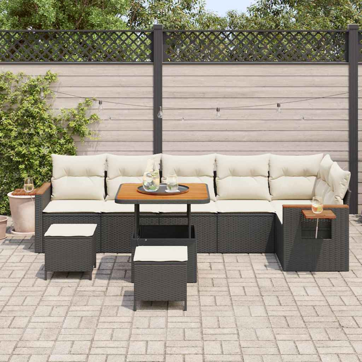 Set da patio esterno con divano componibile, due sgabelli, un tavolo e una recinzione in legno sullo sfondo. Ci sono bevande sul tavolo.