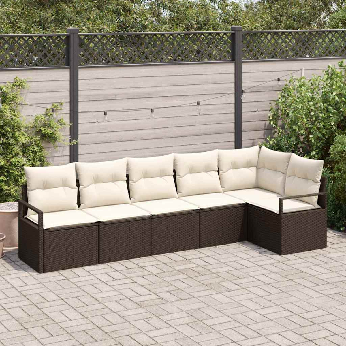 Ein Ecksofa im Freien mit cremefarbenen Kissen. Es steht auf einer Backsteinterrasse, mit Zaun und Grün im Hintergrund.