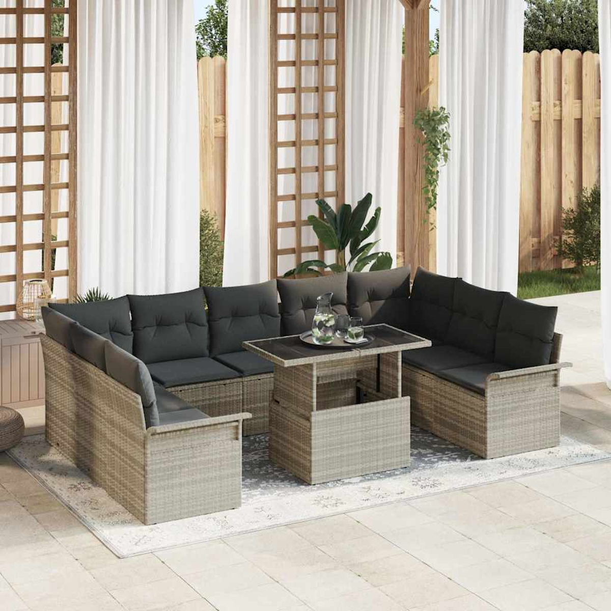 Gartenmöbel-Set mit grauen Kissen und einem Couchtisch. Weiße Vorhänge und Holzzaun im Hintergrund.