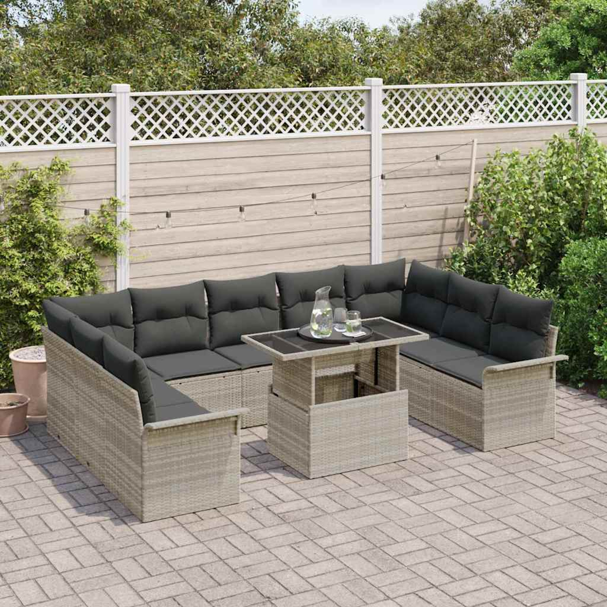 Terrassenset mit grauen Kissen und einem Tisch. Die Szene umfasst einen Zaun und Grün, was eine entspannende Atmosphäre schafft.
