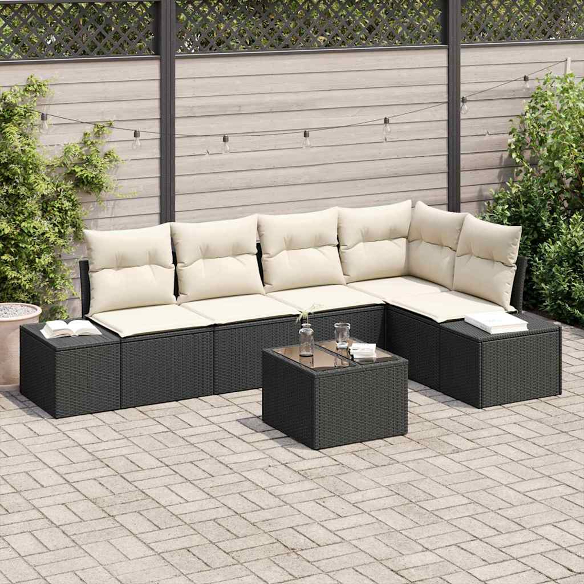 Outdoor-Ecksofa mit cremefarbenen Kissen. Davor steht ein kleiner Tisch mit Gläsern. Im Hintergrund ist ein Zaun zu sehen.