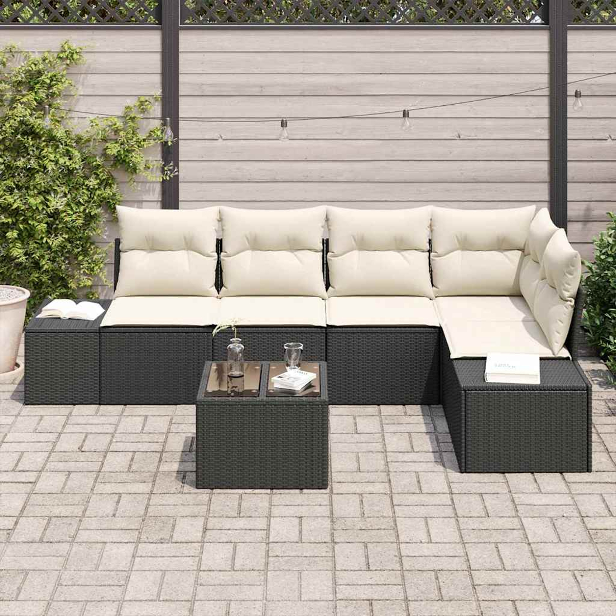Outdoor-Ecksofa mit beigefarbenen Kissen, kleinem Tisch und einem Buch. Der Hintergrund zeigt einen Holzzaun und Grün.
