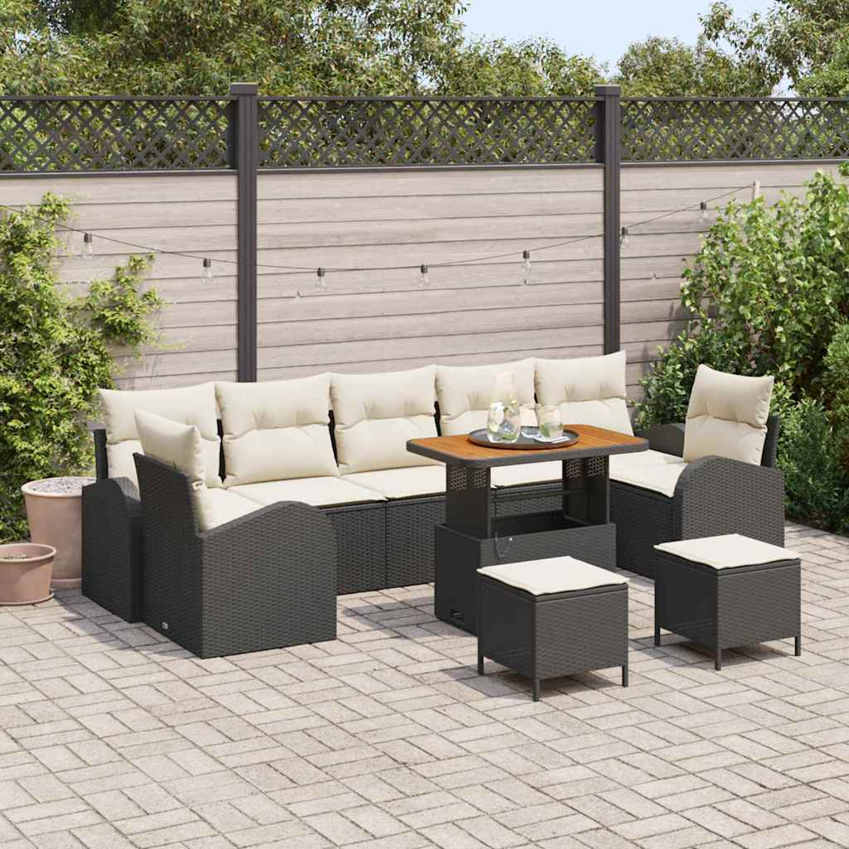 Conjunto de patio al aire libre con sofá, dos sillas, dos otomanas y una mesa. Cojines beige, mimbre gris y mesa de madera. Fondo con valla.