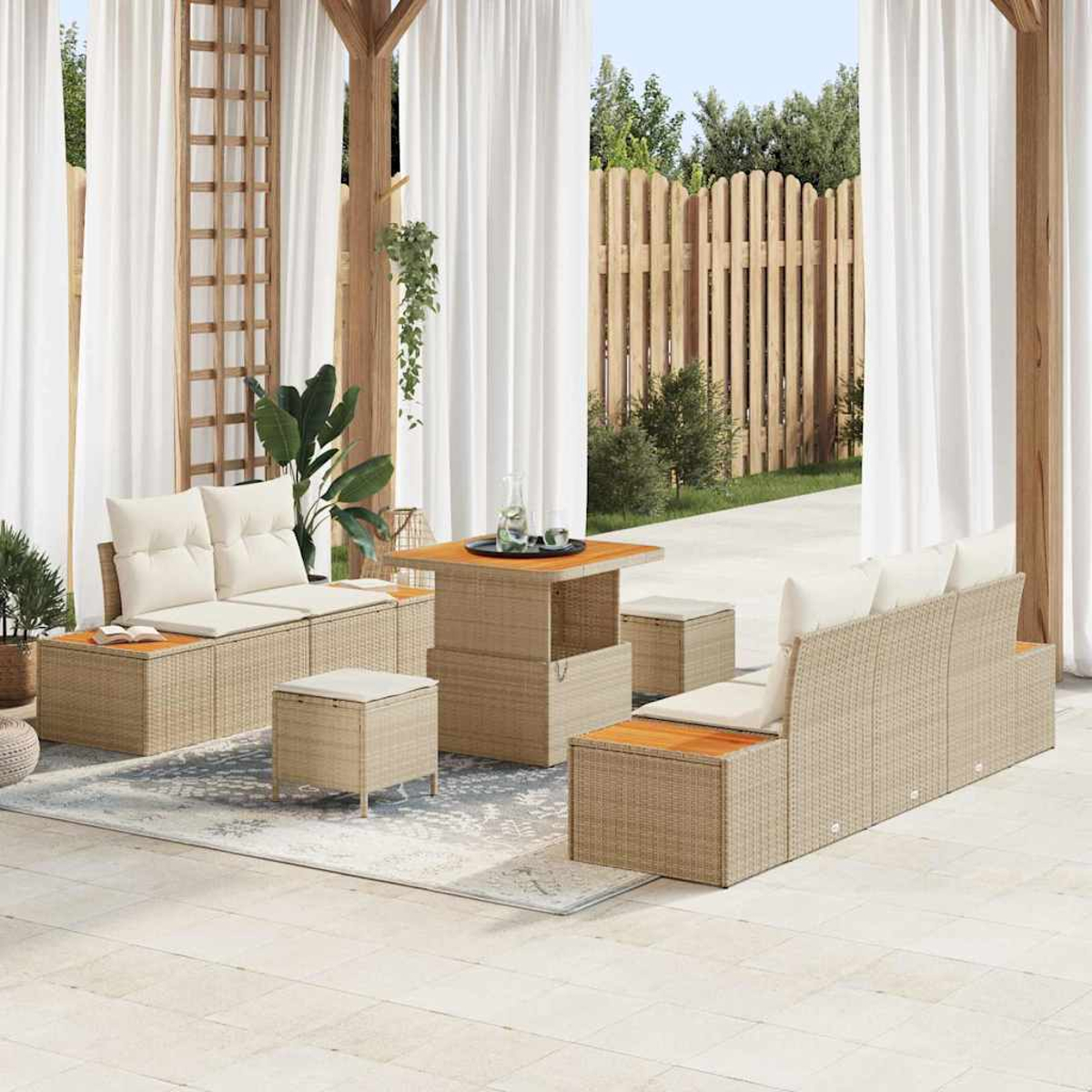 Gartenmöbel-Set mit Rattanmöbeln, Kissen und einem Tisch. Weiße Vorhänge und Holzzaun im Hintergrund.