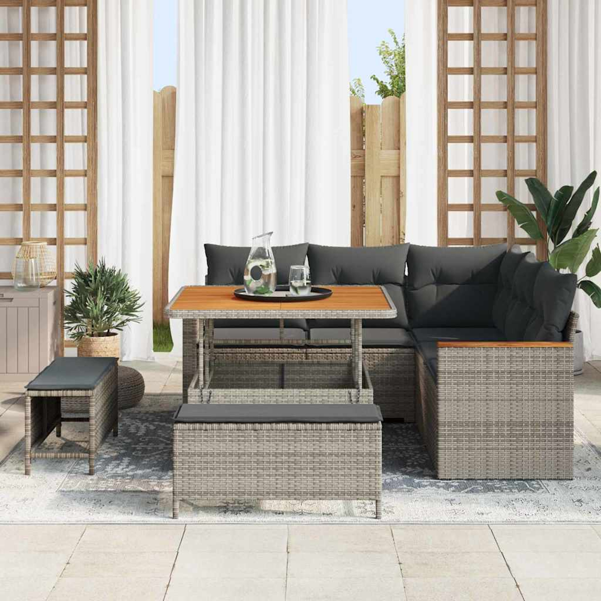 Garten-Set mit grauen Kissen, Holztisch und Pflanzen. Weiße Vorhänge und Holzzaun im Hintergrund.