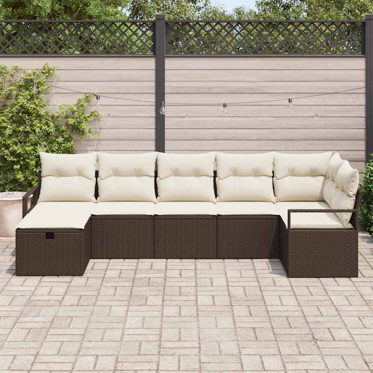 Ein braunes Outdoor-Sofa aus Korbgeflecht mit cremefarbenen Kissen. Im Hintergrund ein Holzzaun und einige Pflanzen.