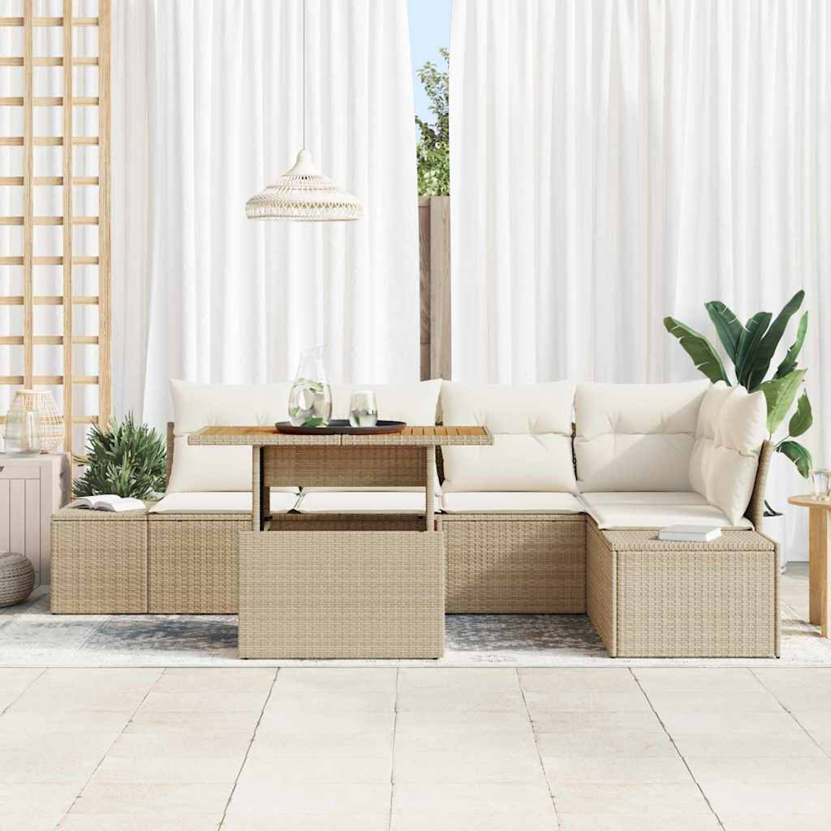 Rattan-Sofa-Set für den Außenbereich mit cremefarbenen Kissen und Holztisch. Weiße Vorhänge und eine Pflanze im Hintergrund.