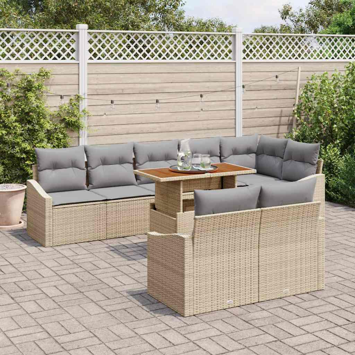 Garten-Rattansofa-Set mit grauen Kissen und einem Holztisch auf einer Ziegelterrasse, im Hintergrund ein Zaun.