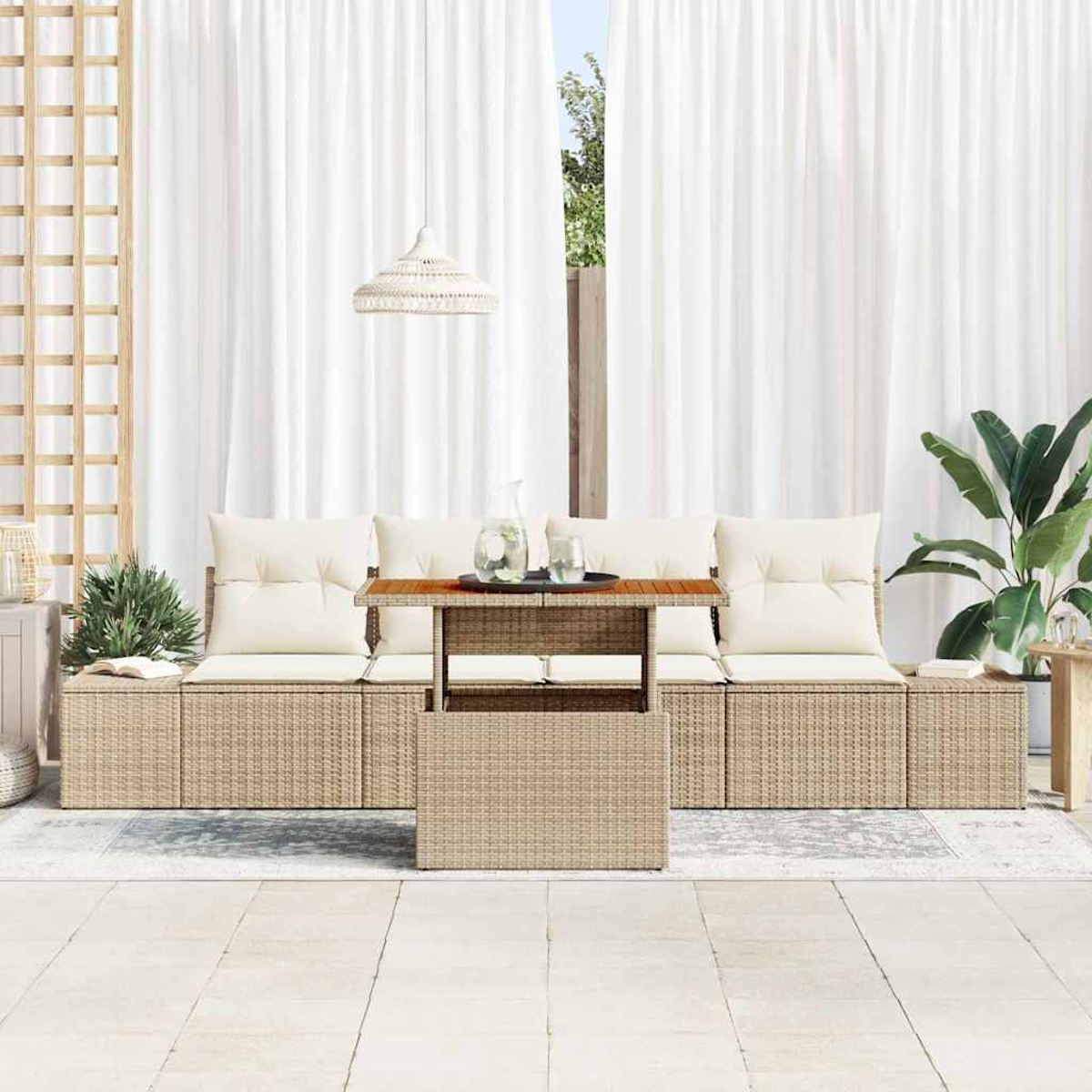 Outdoor-Sitzbereich mit Rattanstühlen, weißen Kissen und Holztisch. Weiße Vorhänge und Pflanzen im Hintergrund.