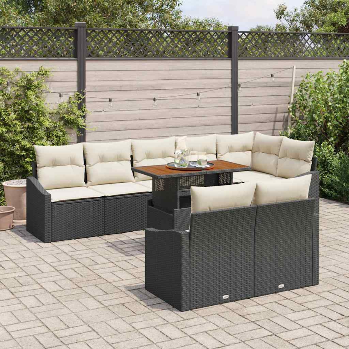 Graues Outdoor-Ecksofa mit beigefarbenen Kissen und einem Holztisch. Die Szene umfasst einen Zaun, Pflanzen und eine Ziegelterrasse.