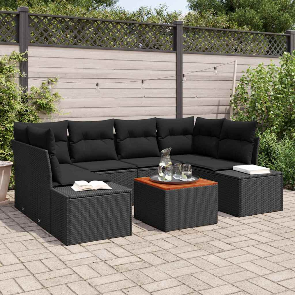 Schwarzes Outdoor-Ecksofa aus Korbgeflecht mit schwarzen Kissen, einem Couchtisch mit Gläsern und einer Holzplatte. Backstein-Terrasse mit Zaun.