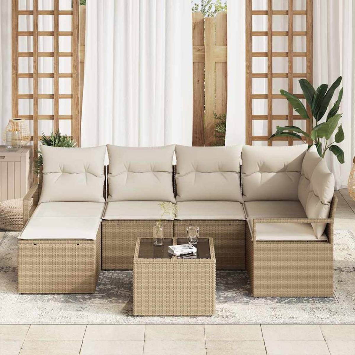 Outdoor-Ecksofa mit beigen Kissen. Vor dem Sofa steht ein kleiner Tisch mit Glasplatte und eine Pflanze. Im Hintergrund weiße Vorhänge.