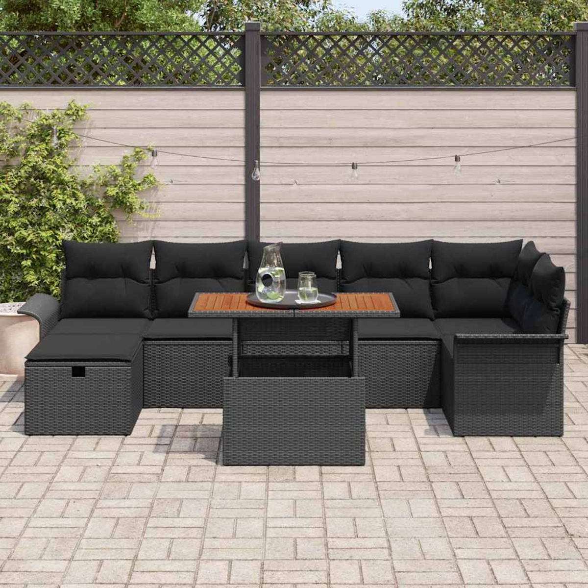 Eine Terrasse mit schwarzem Korbsessel, Holztisch und einem Glas Wasser. Im Hintergrund ein Holzzaun.