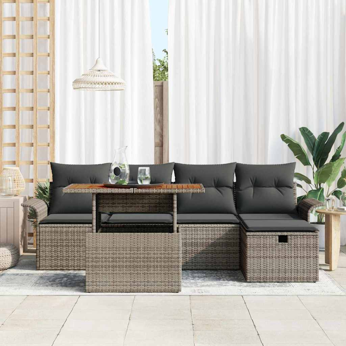 Outdoor-Rattan-Möbelset mit grauen Kissen und einem Tisch. Weiße Vorhänge und eine Pflanze im Hintergrund.