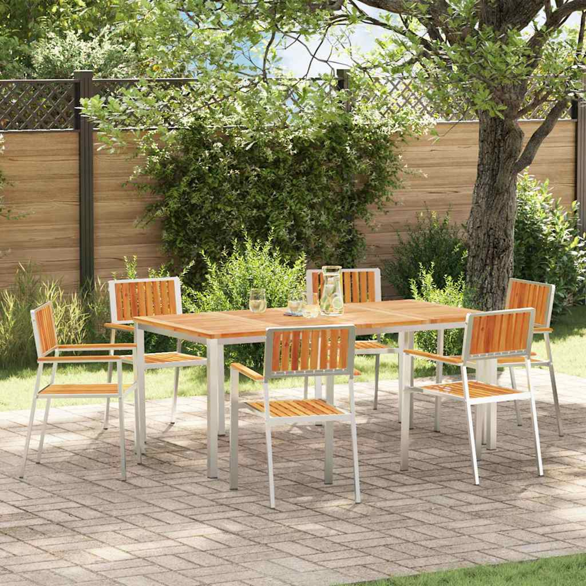Szene auf der Terrasse im Freien mit einem Holztisch und sechs Stühlen. Grünes Laub und ein Holzzaun im Hintergrund. Ziegelterrasse.