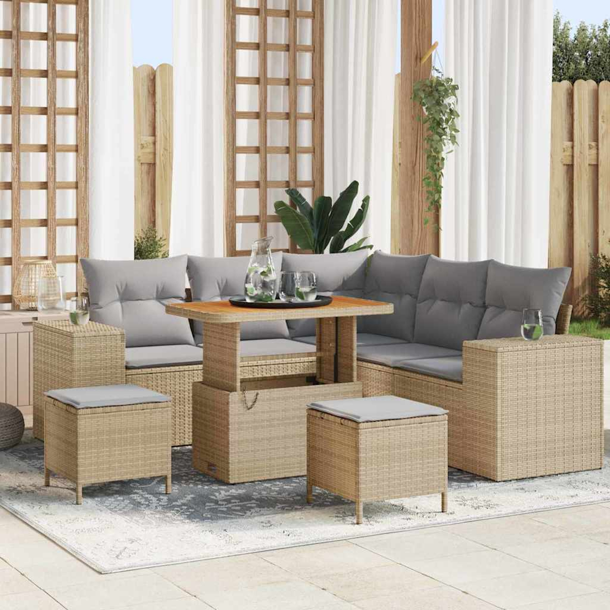 Garten-Sofa-Set: Rattan-Sofa mit grauen Kissen, Tisch und Hockern. Weiße Vorhänge und Holzgitter im Hintergrund.